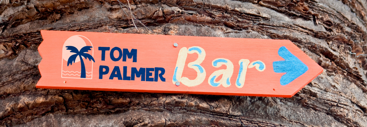 Letrero Tom Palmer Bar sobre un tronco de árbol